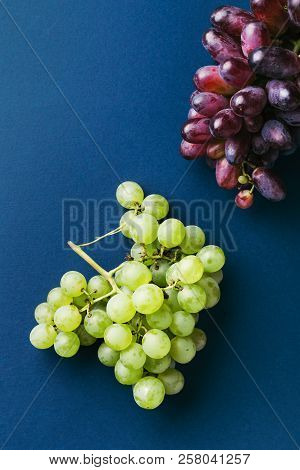 Two Bunches Of Red And Green Ripe Grapes On Dark Blue Background. Top View.
