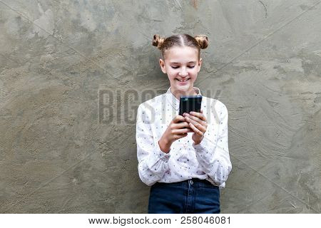 Attractive Caucsian Teenage Girl Looking At Her Mobile Phone Screen With Joyful Face With Smile On G