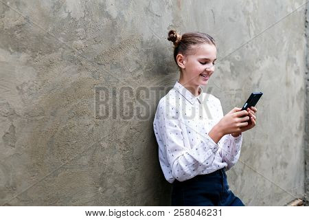 Attractive Caucsian Teenage Girl Looking At Her Mobile Phone Screen With Joyful Face With Smile On G