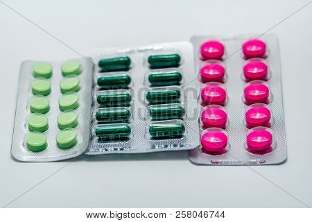 Pink Tablets And Green Capsule And Green Tablets In Blister Pack On White Background. Painkiller Med