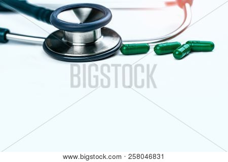 Stethoscope With Four Green Antibiotic Capsule Pills On White Table. Antimicrobial Drug Resistance A