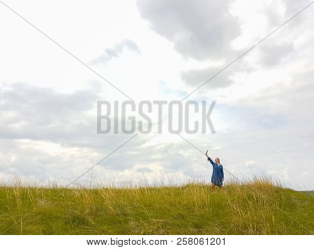 A Young Woman With Red Hair And A Blue Denim Dress Is In The Mountains Outside The City And Is Tryin