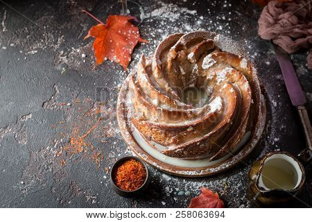 Bundt Cake With Saffron And Rum Covered With White Glaze On Rustic Background With Autumn Decoration