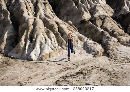 Young Slender Athletic Girl Runs Along A Rough, Deserted Mountainous Terrain