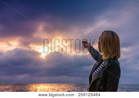 Girl Holding A Glass With Wine Uring The Sunset On The Sea