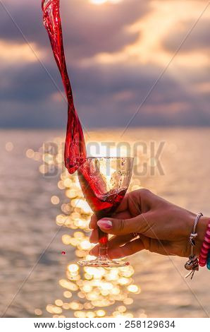 Girl Holding A Glass With Wine Uring The Sunset On The Sea