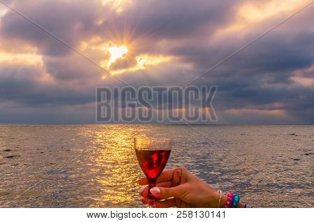 Girl Holding A Glass With Wine Uring The Sunset On The Sea