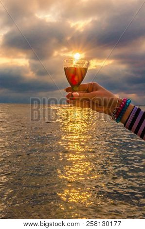 Girl Holding A Glass With Wine Uring The Sunset On The Sea