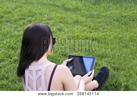 Portrait Of Charming Young Female Working On Portative Computer And Laying On Fresh Green Grass. Pre