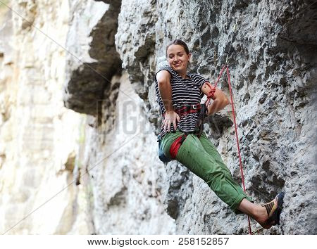 Girl Rock Climber Resting While Climbing On The Cliff