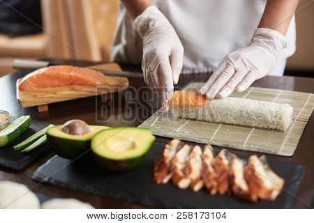 Closeup Viev Of Chef Hands Preparing Japanese Food. Chef Making Sushi Rolls At Restaurant With Many 