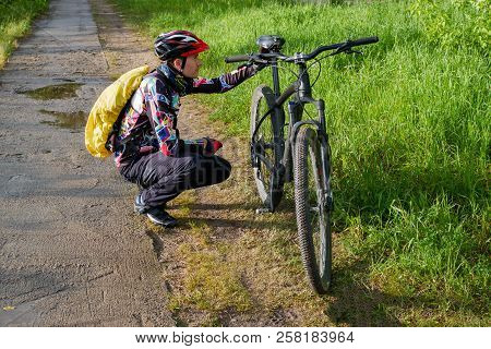 Photo Of Male Cyclist Wearing Helmet Next To Bicycle On Road In Woods During Day
