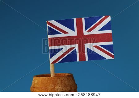 A Detail On Paper National Flag Of United Kingdom On Wooden Stick In Wooden Barrel. Blue Background