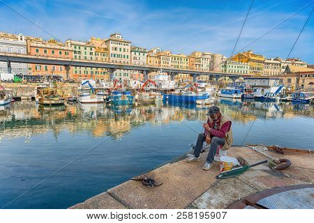 Genoa (genova) Italy, April 12, 2017 - View Of A Fisherman In The Port Of Genoa And The Historic Cen