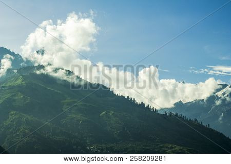 Green Mountain With Snow Peaks In The Clouds