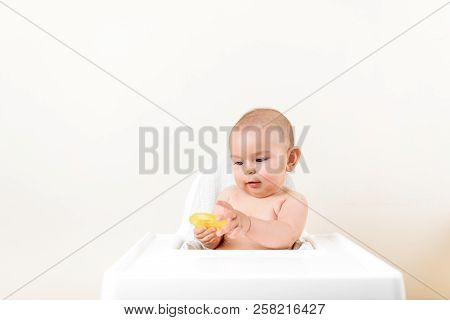 Cute Baby Infant Kid Biting Sitting In Highchair And Chewing Yellow Eething Toy Copy Space Bright Mi