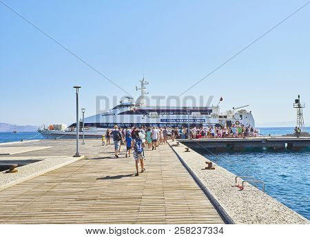 A Herd Of Tourists Boarding In A Ferry. Kos, South Aegean Region, Greece.