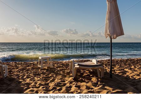 Empty Plastic Sun Lounger And Umbrella On The Sandy Beach