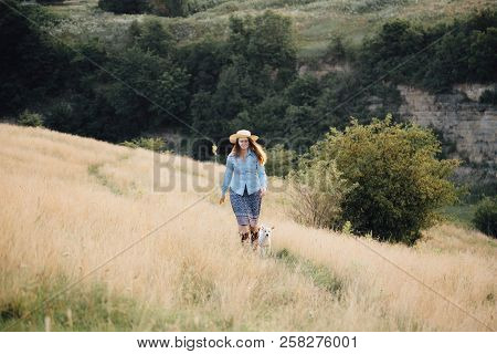 Girl In A Hat Playing With A Dog In The Field At Sunset Sun