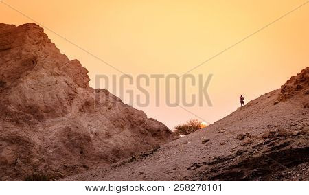 Hiker is watching sunset in Hajar Mountains of Ras Al Khaimah in UAE