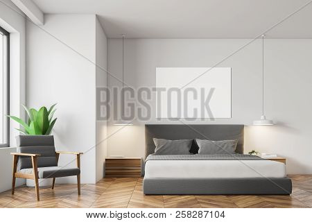 White Wall Minimalistic Bedroom Interior With A Wooden Floor, Masterbed, Night Stand And Gray Armcha