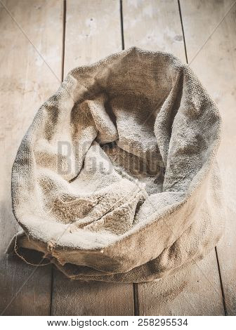 Burlap Bag Of White Wholemeal Flour On Wooden Rustic Boards Background.