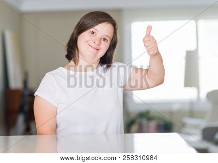 Down syndrome woman at home happy with big smile doing ok sign, thumb up with fingers, excellent sign