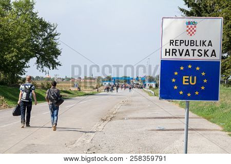 Tovarnik, Croatia - September 19, 2015: Refugees Passing In Front Of The Eu Entrance Sign In Front O
