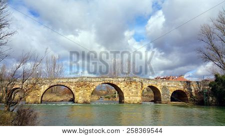Bridge Over The River Cea In The Vicinity Of The City Sahagun, Spain. Silent River, Sunny Day, Cloud