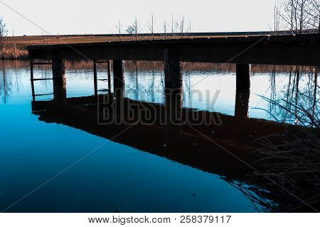 A Picture Taken Of A Pond With A Bridge In It. The Picture Has A Really Nice Shadow And Teal And Ora