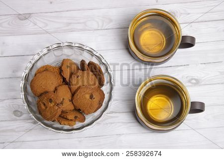 Two cups of green tea with choco chips cookies on white wooden table