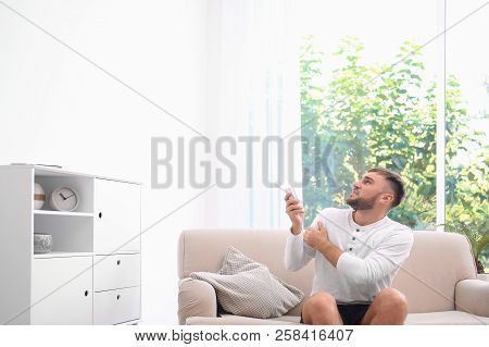 Young Man Suffering From Cold At Home. Air Conditioner Malfunction