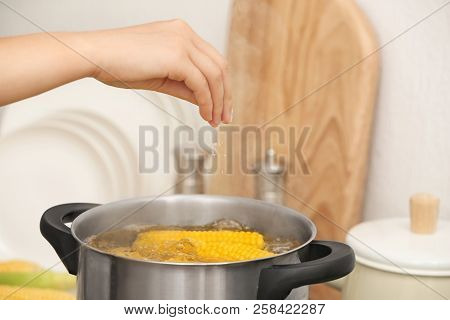 Woman Salting Water With Corn Cobs In Stewpot, Closeup