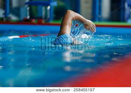Photo of athletic man in blue cap swimming in pool