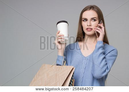 Girl In Blue With Bags Drinking Coffee Talks By Smartphone