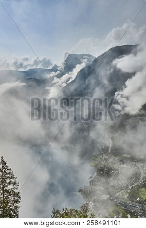 Scenic View Of Misty Mountains Above Halstatt Village In Austria.