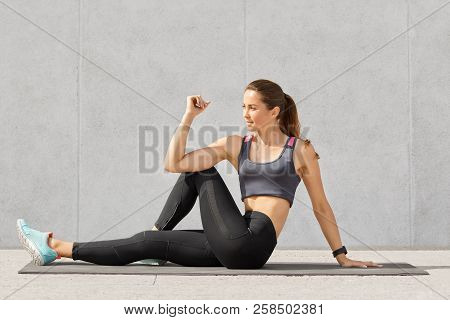 Sporty Fitness Trainer In Casual Top And Leggings, Makes Stretching Exerices For Legs, Sits On Floor