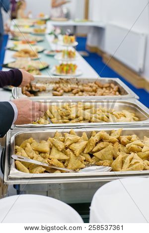 Feast. Table Full Of Food. Fried Rolls, Sousages And Plated. Arm With Spoon.