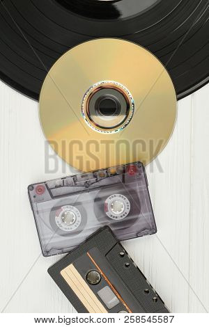 Vinyl Record, Audio Tapes And Compact Disc. Top View On Black Vinyl Plate, Dvd Disc, Audio Cassette 