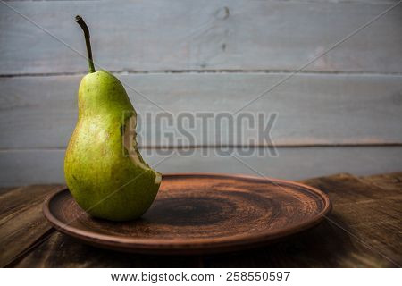 A Bite Pear On A Plate On Wooden Background