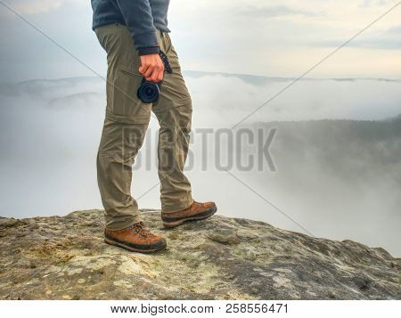 Photographer Hand With  Camera,  Legs, Knees And Boots. Man Takes Landscape Photos On Peak Of Rock. 