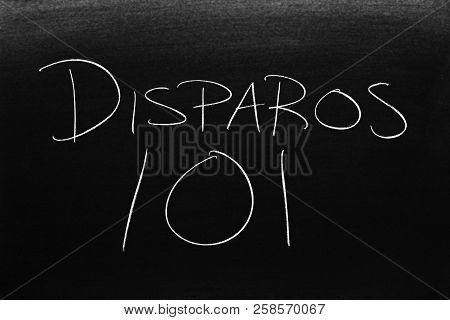 The Words Disparos 101 On A Blackboard In Chalk.  Translation: Shooting 101