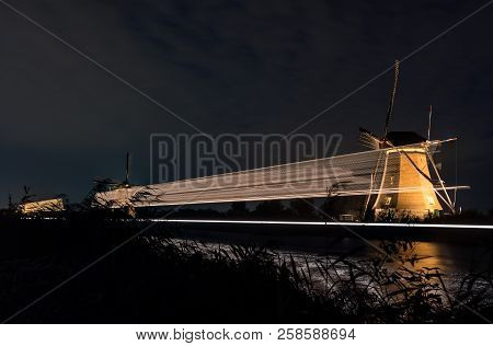 These Beautiful Windmills In Kinderdijk Are Illuminated With White Light At The Blue Hour