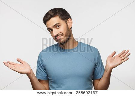 I Don't Know. Portrait Of Young Confused Man In Blue T-shirt Standing And Shrugging Shoulders, Sprea