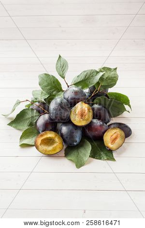 Fresh Plum Fruit With Leaves On A Light Table.