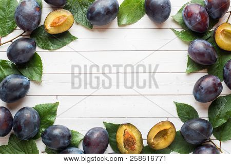 Fresh Plum Fruit With Leaves On A Light Table.