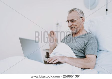 Old Man In Clinic With Laptop. Aged Man In Hospital With Laptop. Rehabilitation Patient In Clinic. H