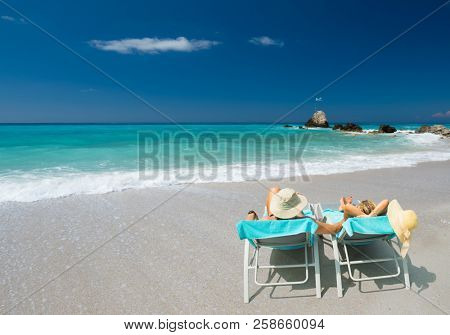 Couple on sunbeds relaxing at the beach in Lefkada Greece