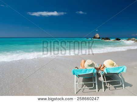 Couple on sunbeds relaxing at the beach in Lefkada Greece
