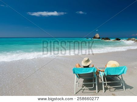 Couple on sunbeds relaxing at the beach in Lefkada Greece